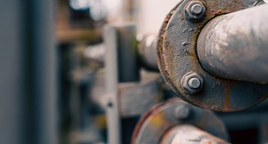 Close-up view of rusted industrial pipes with bolts, showcasing weathering and texture.